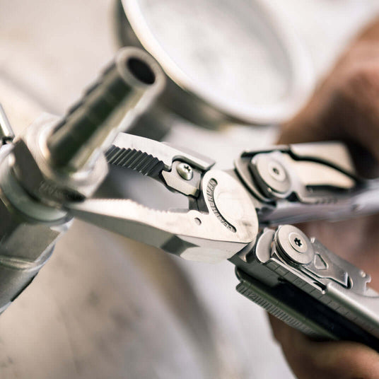 Translation missing: de.A person using the pliers on a Leatherman Surge to tighten nut on bolt, demonstrating practical skills with tools in a hands-on setting