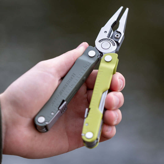 Translation missing: es.Mossy Slate Rebar held in a hand, open to showcase it's pliers, against a blurred background