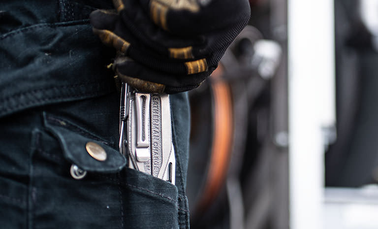 Translation missing: de.Man with dirty black and yellow gloves pulling Charge+ TTI out of back jean pocket