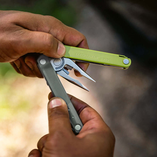 Translation missing: nl.A close-up of hands holding the Mossy Slate Leatherman Bond® multitool, showcasing its sleek design and functionality