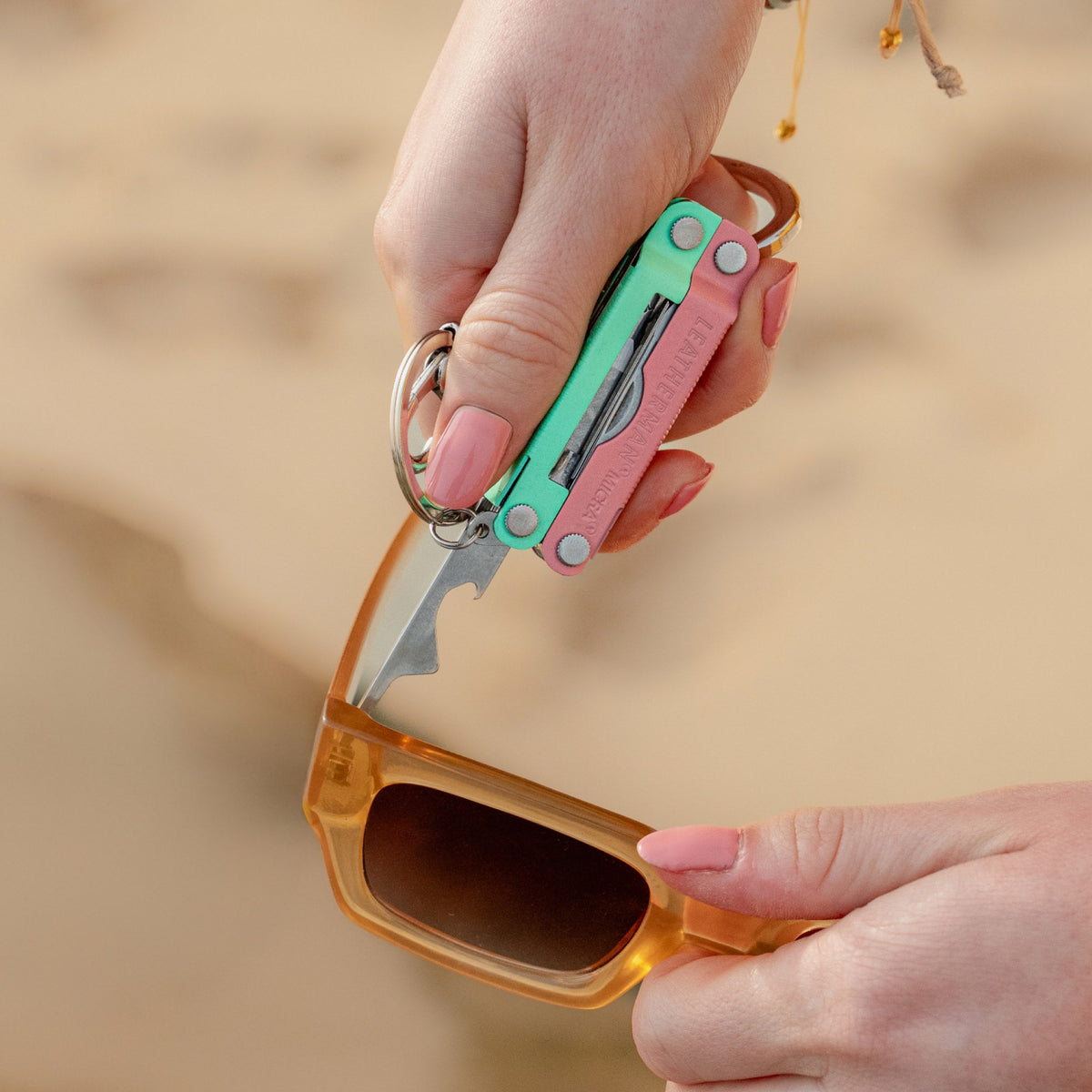 Translation missing: es.Person using the extra small screwdriver on a Leatherman Micra® in Bayside color to tighten sunglasses on the beach