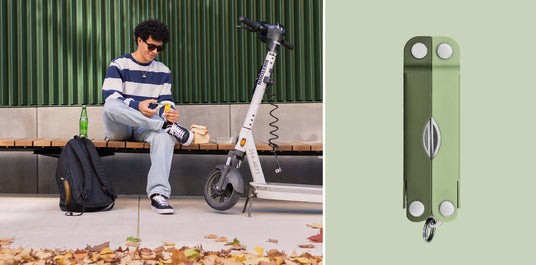 Translation missing: de.A man using the scissors on a Micra® multitool in Cardamom color to open a food packet while sitting on a bench next to a backpack and electric scooter