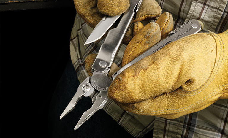Translation missing: de.Man in green plaid shirt and yellow leather gloves pulling knife blade out of Leatherman Super Tool 300