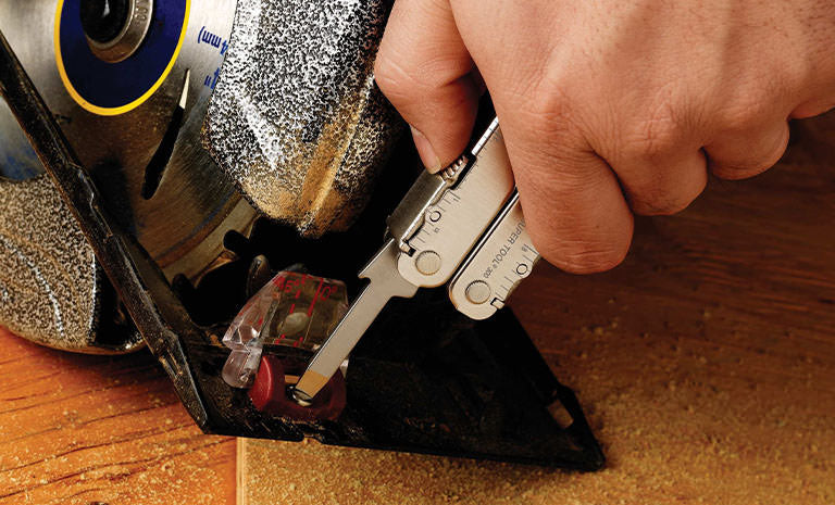 Translation missing: de.Man using Leatherman Super Tool 300 to tighten screw on saw machine