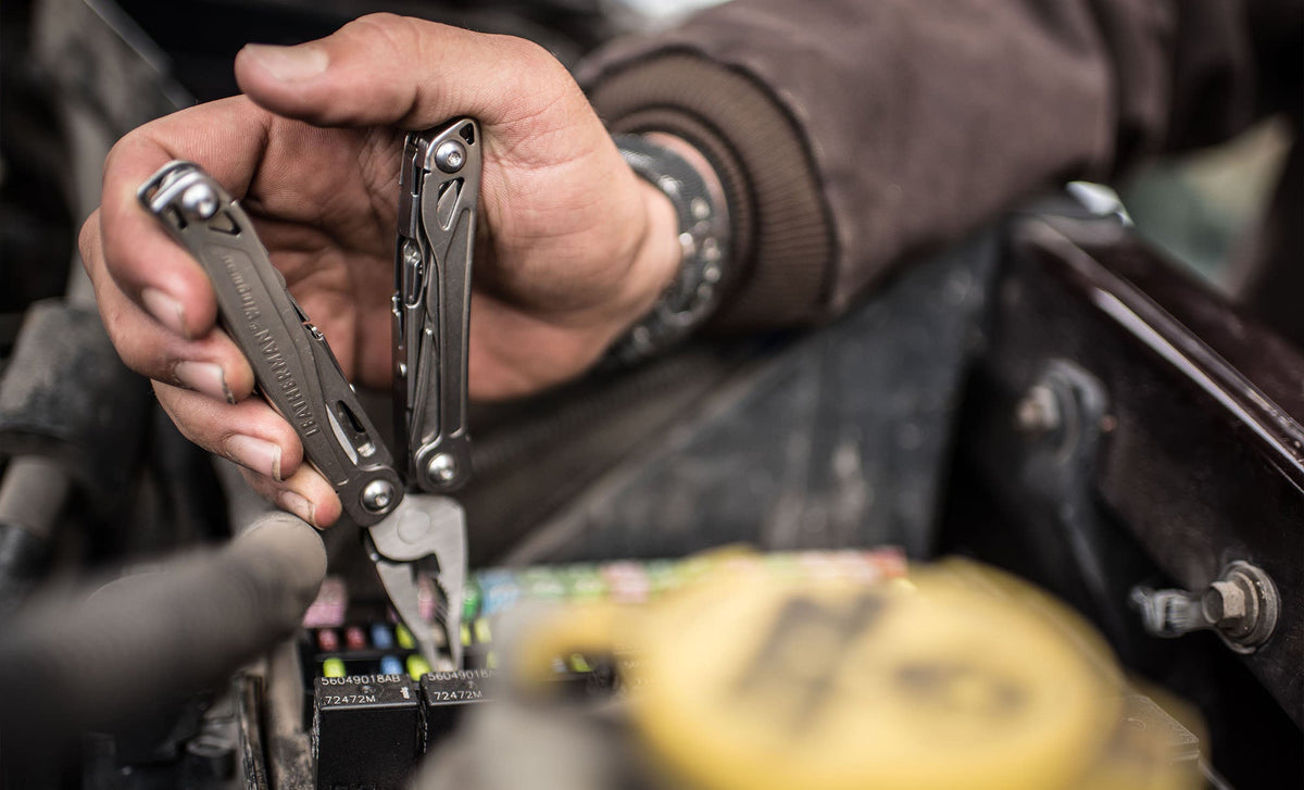 Translation missing: es.Hand using a stainless steel Leatherman Wingman® pliers to remove a fuse from a vehicle's electrical system