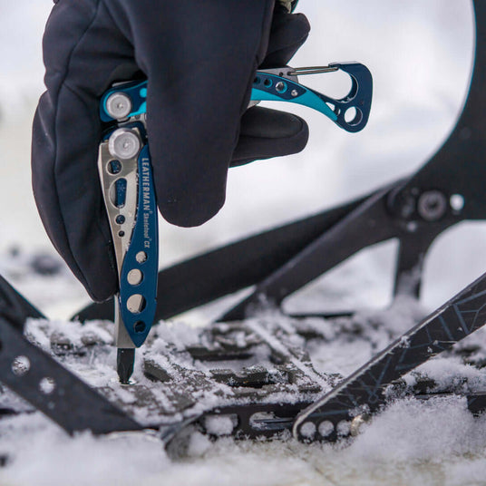 Translation missing: de.Someone using a Skeletool CX to tighten the binding on a snowboard