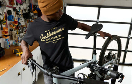 Translation missing: de.Person assembling a bicycle in a workshop wearing a black Leatherman Vintage Tee