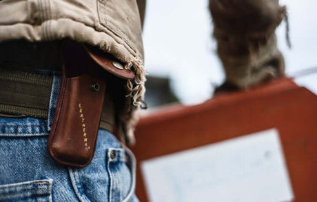 Translation missing: de.Close-up photo of a person wearing blue denim jeans with a brown Leatherman sheath attached on the belt
