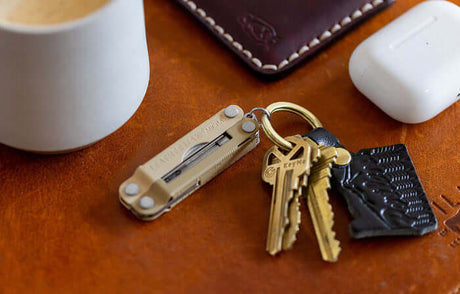 Translation missing: de.Leatherman micra with key on key ring next to coffee cup and airpods. 