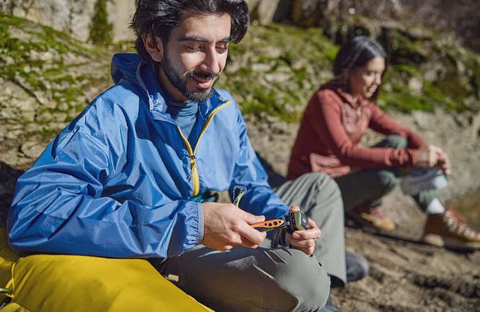Translation missing: de.Person using a Skeletool CX in Aurora color while sitting outdoors, enjoying nature with a friend in the background