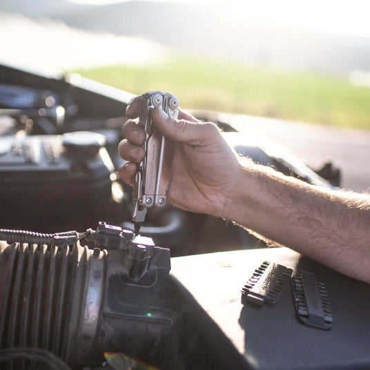 Translation missing: de.Leatherman Surge being used to work on a truck with a bit kit set