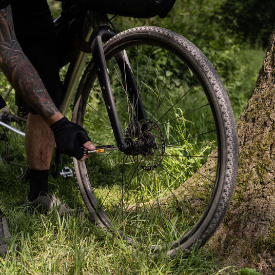 Translation missing: es.Person repairing a bicycle’s front wheel outdoors using Leatherman Signal