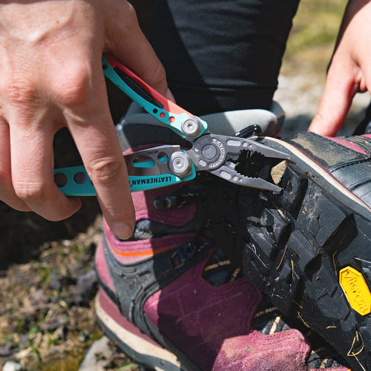 Translation missing: es.Leatherman Skeletool CX pliers used to remove a stone stuck in the sole of a hiking boot
