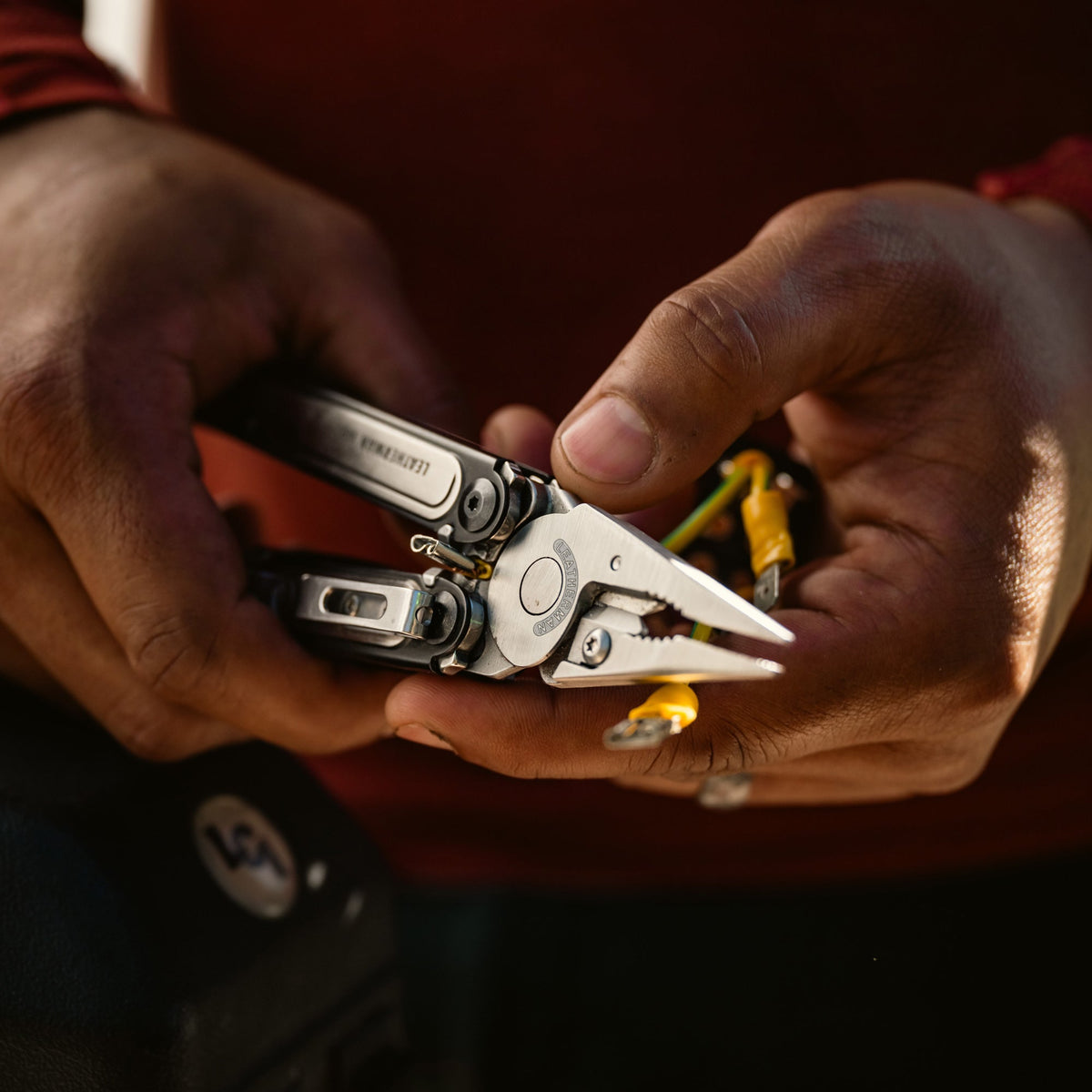 Translation missing: de.Person cutting rope with a Black DLC stainless steel Leatherman ARC® in a grassy outdoor setting