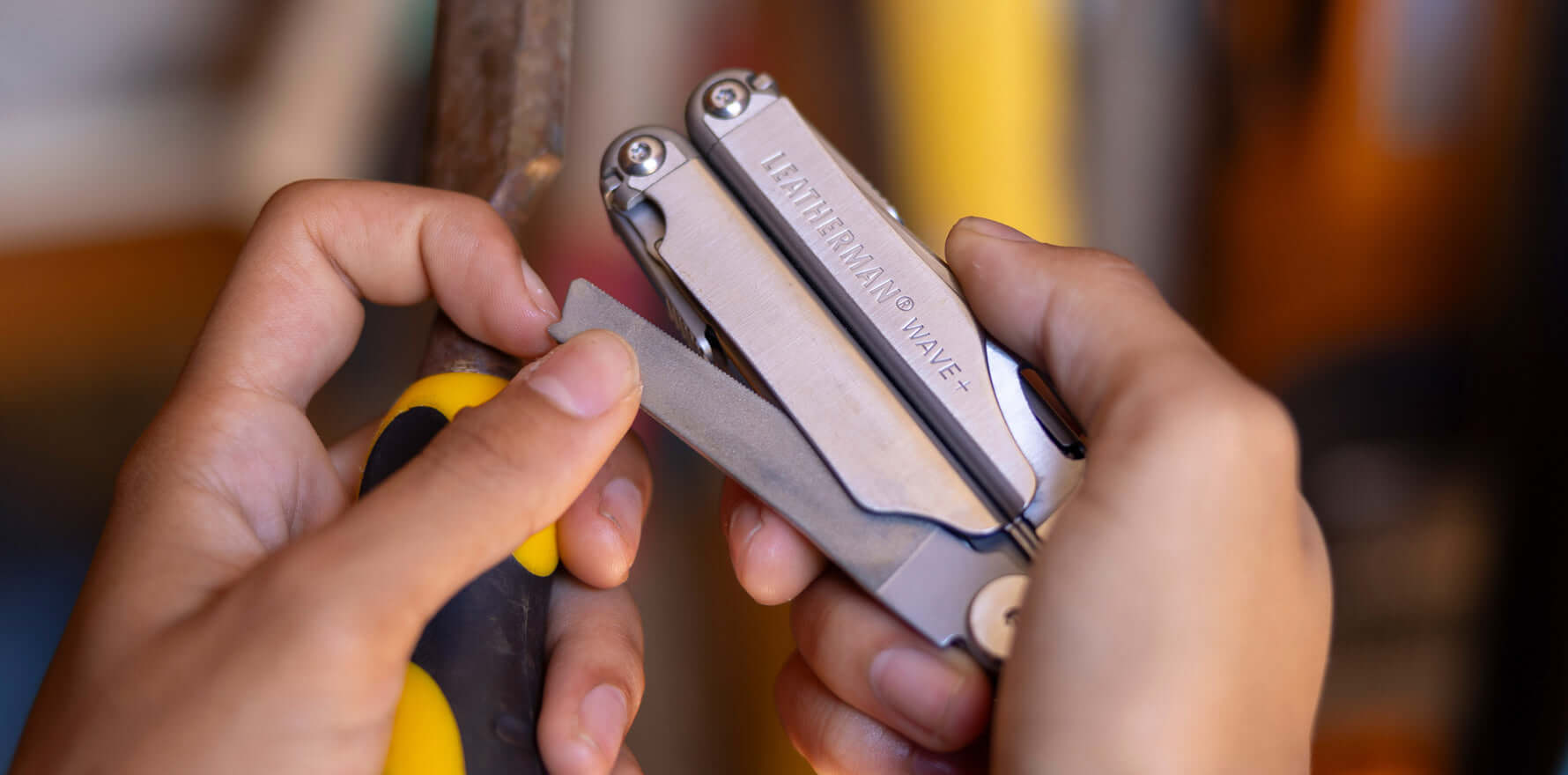 Person holding a Leatherman Wave Plus multitool, opening the diamond-coated file to sharpen a wood chisel.