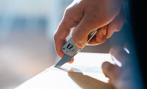 Translation missing: de.Man using box opener on Leatherman T2 to open brown box