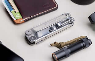 Translation missing: de.A collection of items including a wallet, a cell phone, Leatherman Curl and a flashlight arranged on a flat surface