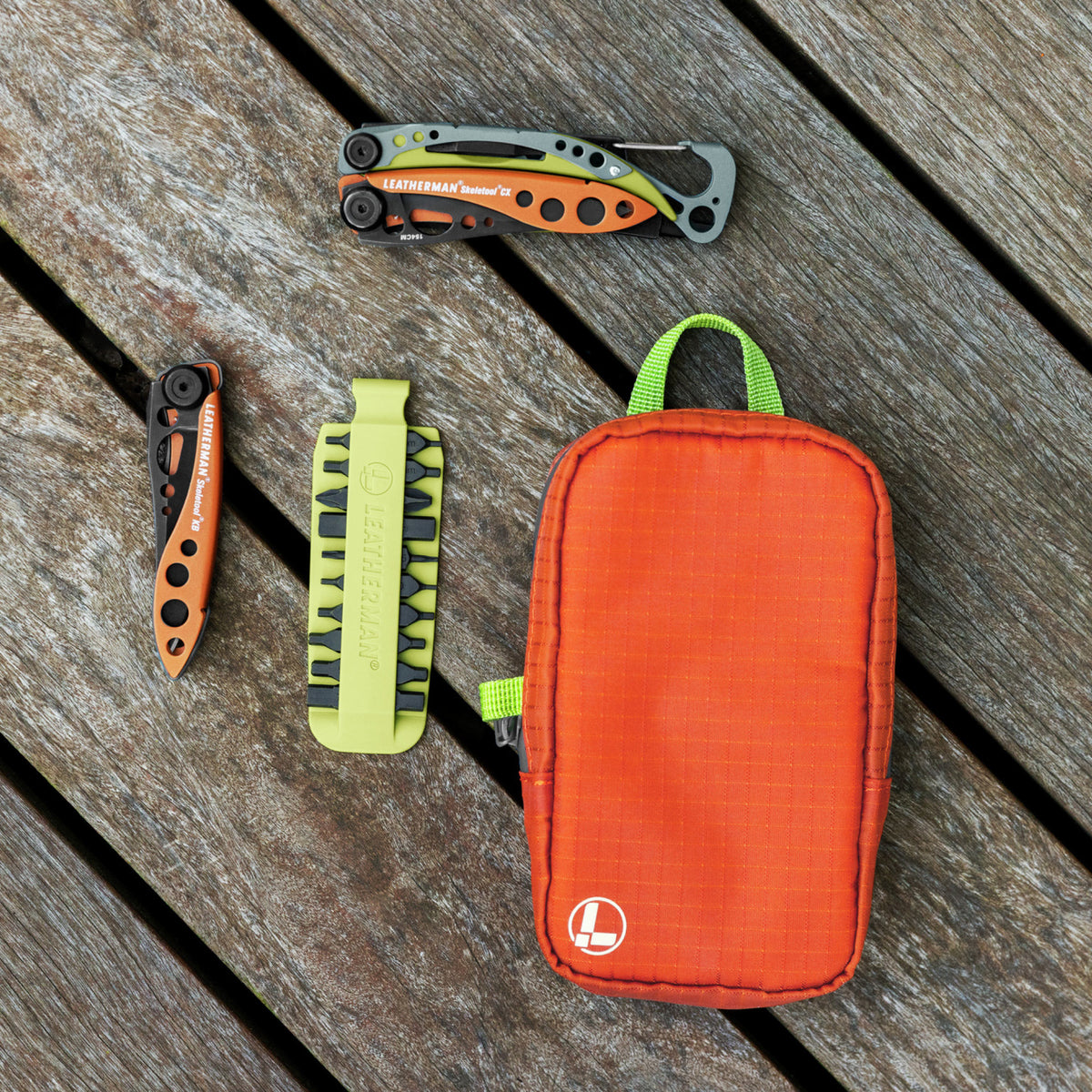 Translation missing: es.Aurora Leatherman tool pouch with bright zipper pull beside multitools and bit kit on wooden surface
