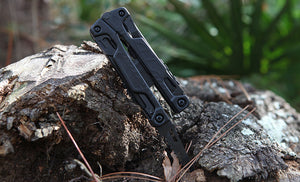 Black Leatherman OHT saw blade inside a piece of wood outdoors