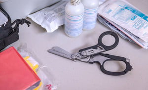 Translation missing: de.Black Leatherman Raptor® Rescue open on a desk with first aid supplies