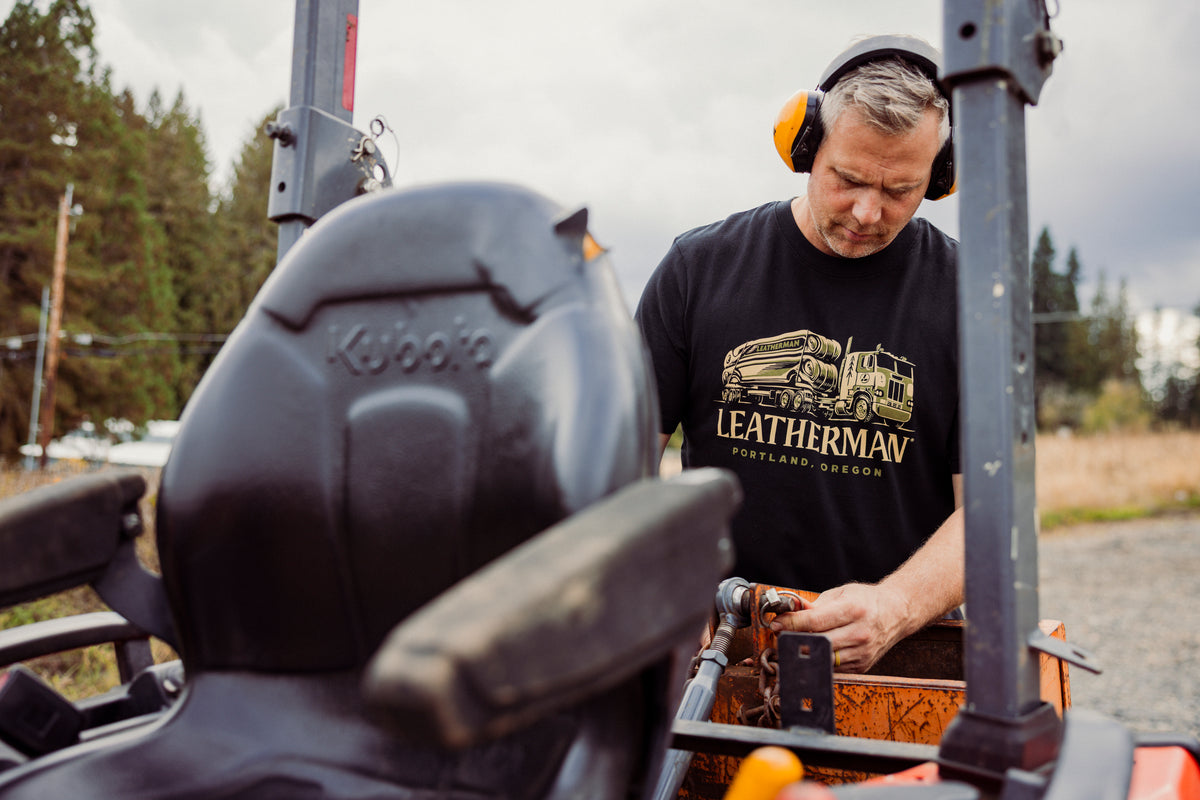 Translation missing: de.A person wearing a black Leatherman Timber Tee working on a tractor outdoors