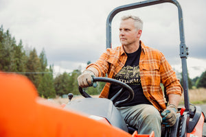 Translation missing: de.A person wearing a black Leatherman Timber Tee driving a tractor outdoors
