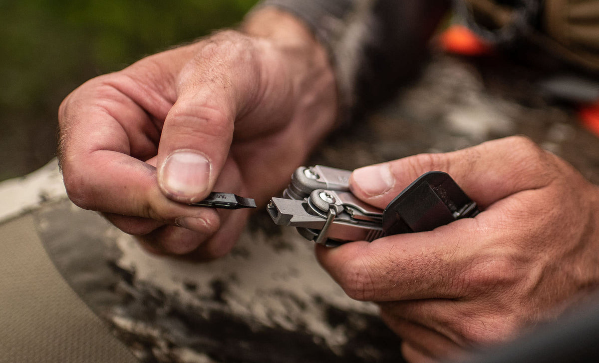 Translation missing: de.Hands inserting a bit into a Stainless Steel Leatherman Wave® Plus multitool outdoors