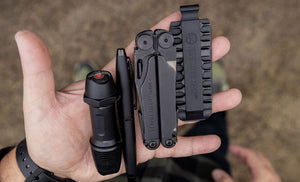 Translation missing: de.Hands showcasing a Black Leatherman Wave® Plus, bit kit, pen, and flashlight
