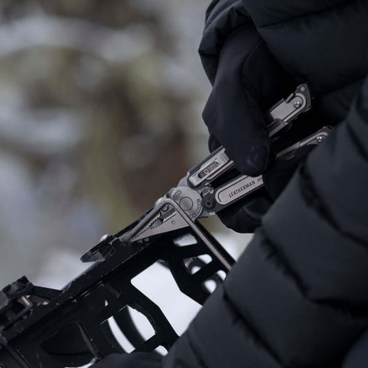 Translation missing: de.Someone using the pliers on a Leatherman ARC to fix a binding on a snowboard